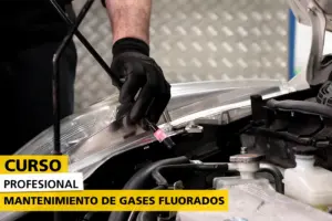 Primer plano de un mecánico con guantes negros realizando mantenimiento en el motor de un vehículo. En la imagen se muestra el texto 'CURSO PROFESIONAL - MANTENIMIENTO DE GASES FLUORADOS' en una franja amarilla y blanca, destacando la formación especializada en el área automotriz.