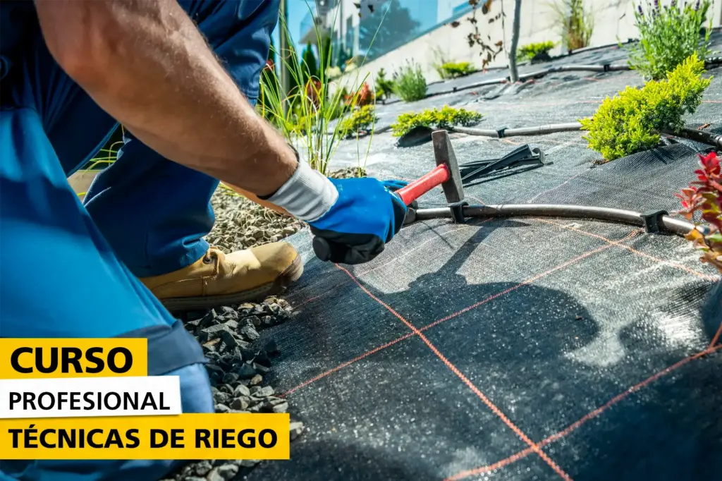 Persona instalando un sistema de riego por goteo en un jardín cubierto con malla antihierbas, usando un martillo para fijar las tuberías, como parte de un curso profesional sobre técnicas de riego.