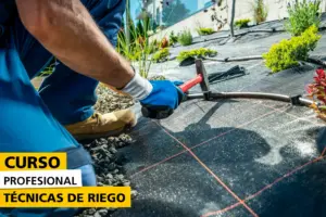 Persona instalando un sistema de riego por goteo en un jardín cubierto con malla antihierbas, usando un martillo para fijar las tuberías, como parte de un curso profesional sobre técnicas de riego.
