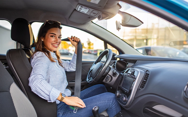 conductora utilizando el cinturón de seguridad en un turismo, representando los sistemas de seguridad activa y pasiva para una conducción segura y la prevención de accidentes.